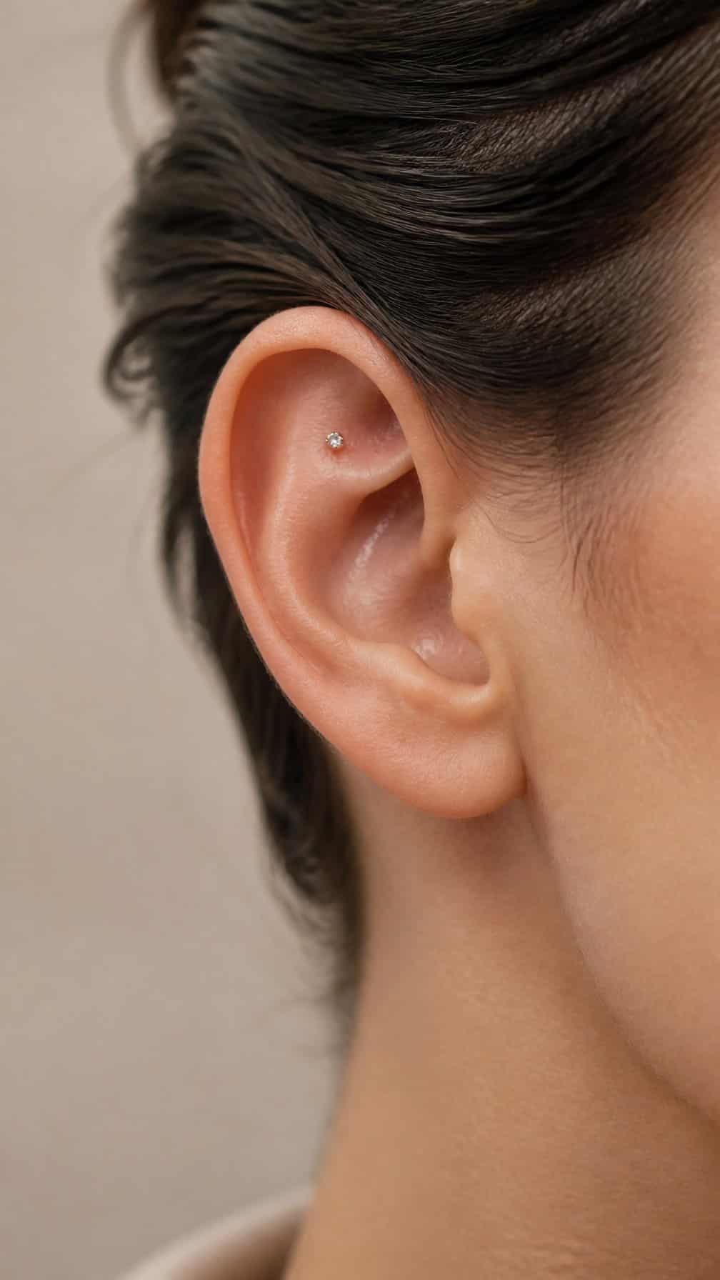 Close-up of an ear with a tiny gemstone snug piercing in the upper inner cartilage.