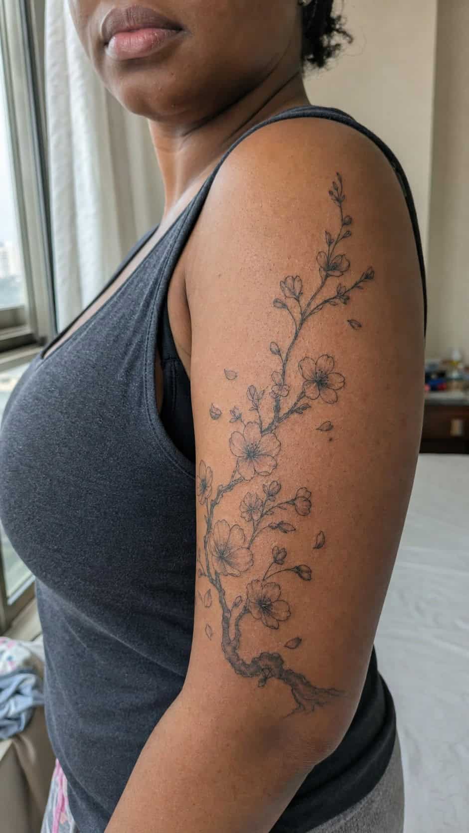 Empowering and Beautiful: 23 Japanese Tattoos for the Modern Woman 4 Healed cherry blossom serenity tattoo on a adult woman's outer upper arm, photographed in a natural casual close three-quarter view — study 1