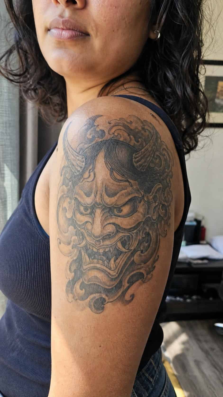 Empowering and Beautiful: 23 Japanese Tattoos for the Modern Woman 28 Healed mask of the oni tattoo on a adult woman's shoulder, photographed in a natural waist-height candid close-up — study 1