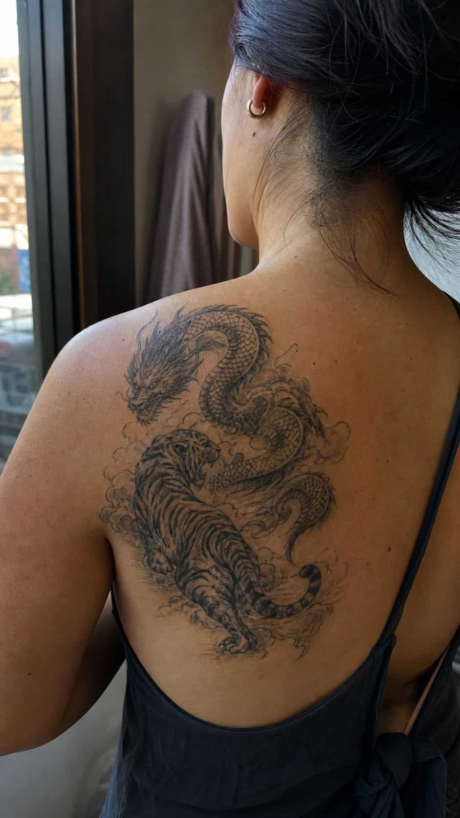 Empowering and Beautiful: 23 Japanese Tattoos for the Modern Woman 31 Healed dragon and tiger duo tattoo on a adult woman's upper back, photographed in a natural relaxed documentary crop — study 1