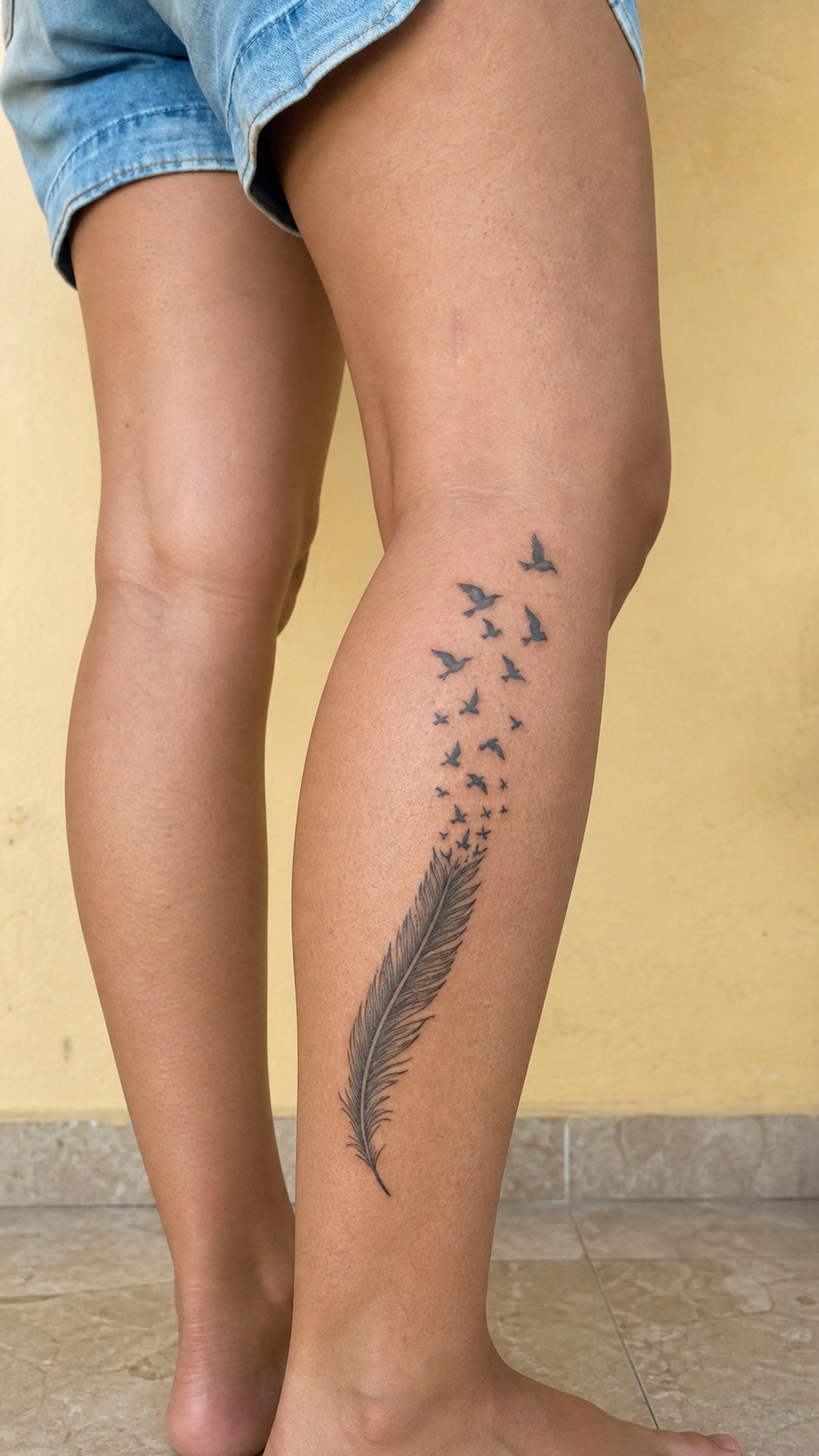 38 Creative Tattoo Ideas for Women 19 Healed feather with birds tattoo on a adult woman's outer calf, photographed in a natural relaxed documentary crop — study 1
