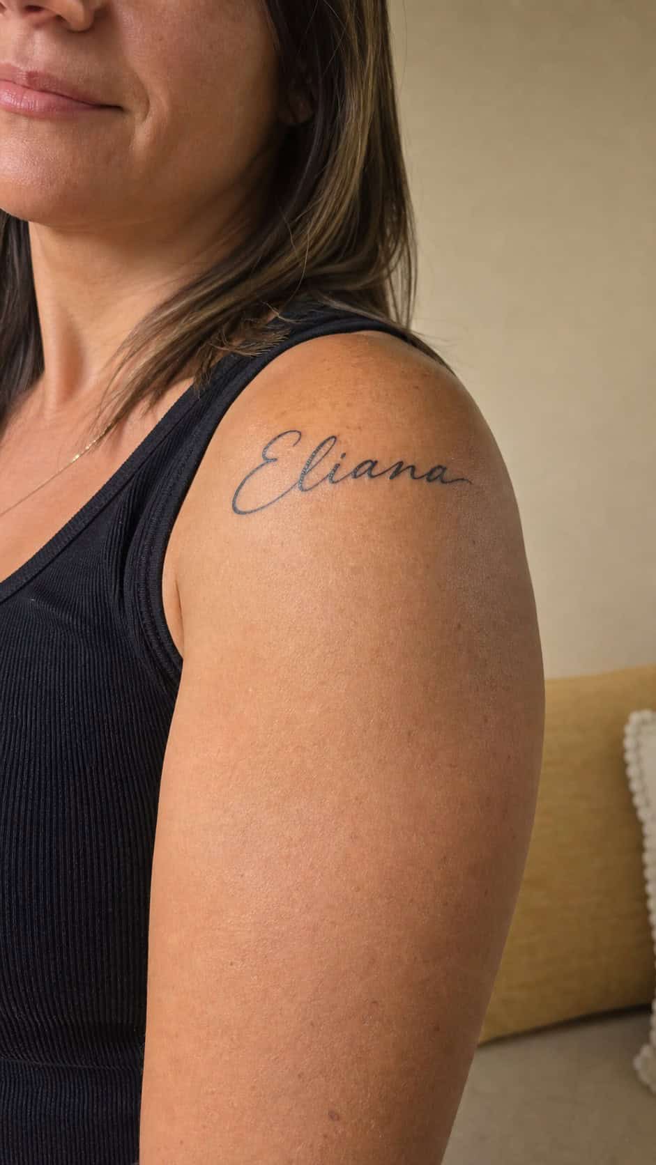 Healed personalized name script tattoo on a adult woman's shoulder, photographed in a natural slightly elevated close view — study 1
