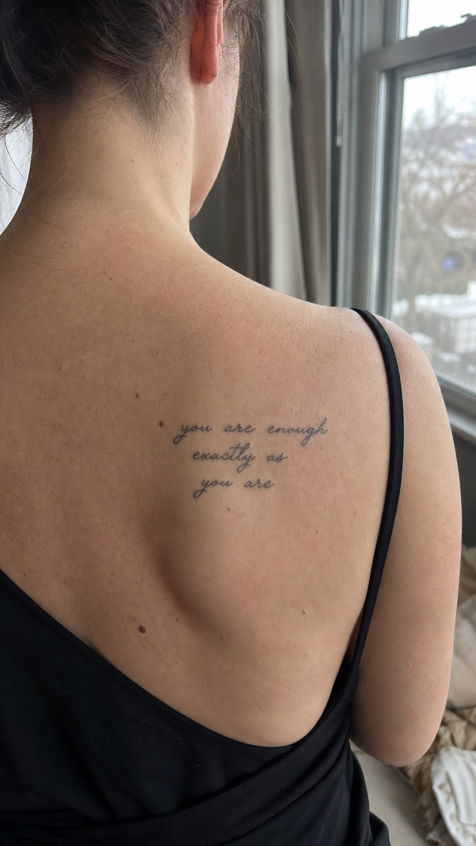 Healed motivational quote tattoo on a adult woman's upper back, photographed in a natural slightly elevated close view — study 2