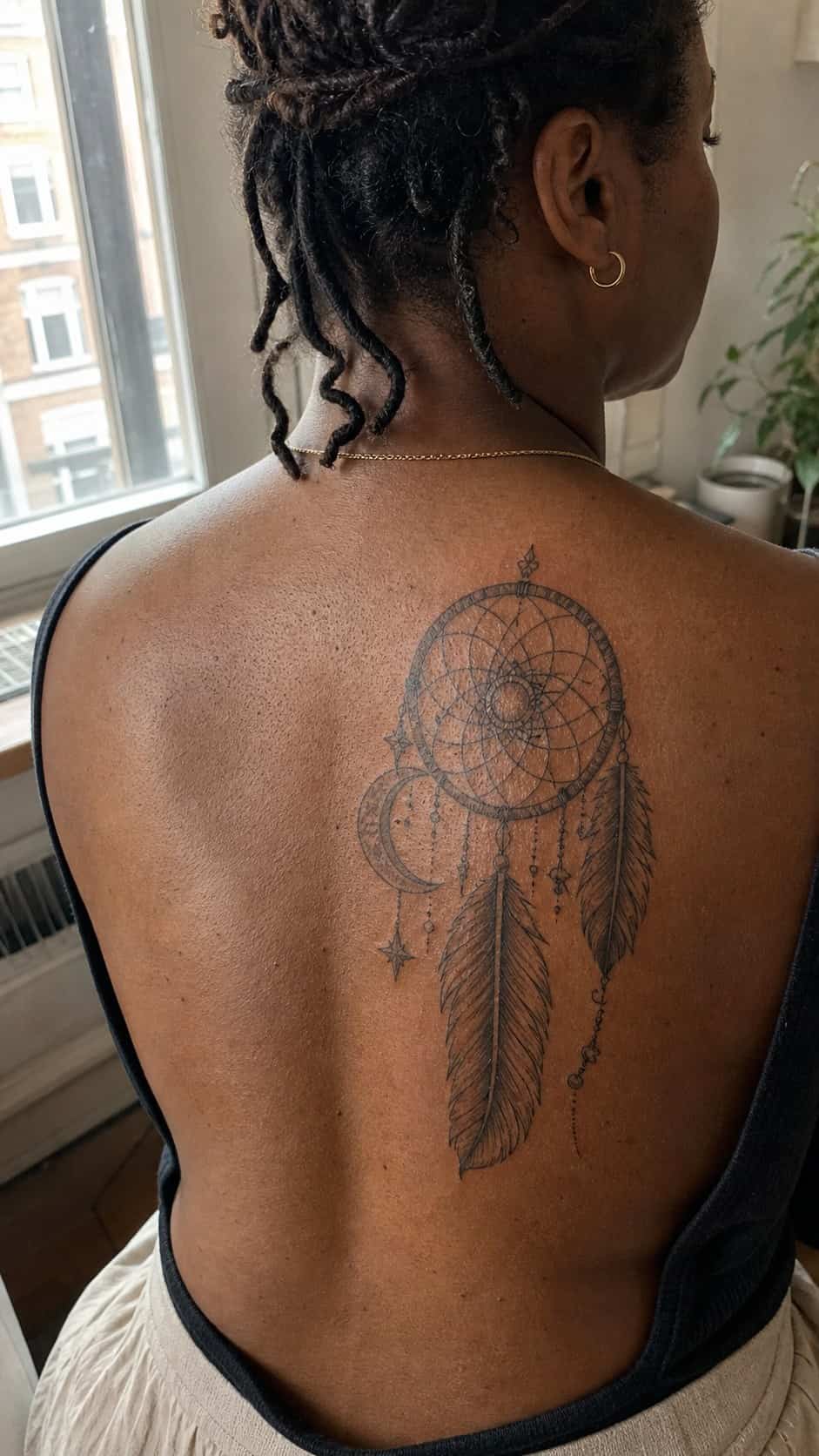 Healed mystical dreamcatcher tattoo on a adult woman's upper back, photographed in a natural slightly elevated close view — study 1
