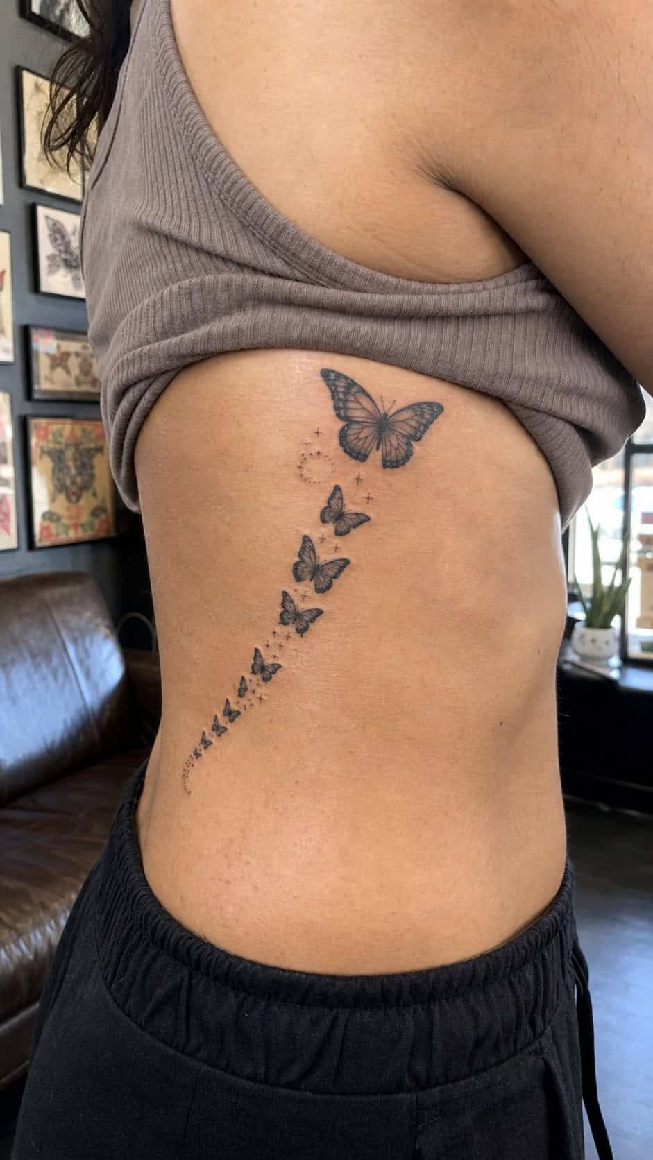 Healed butterfly flight tattoo on a adult woman's side ribs, photographed in a natural casual close three-quarter view — study 2