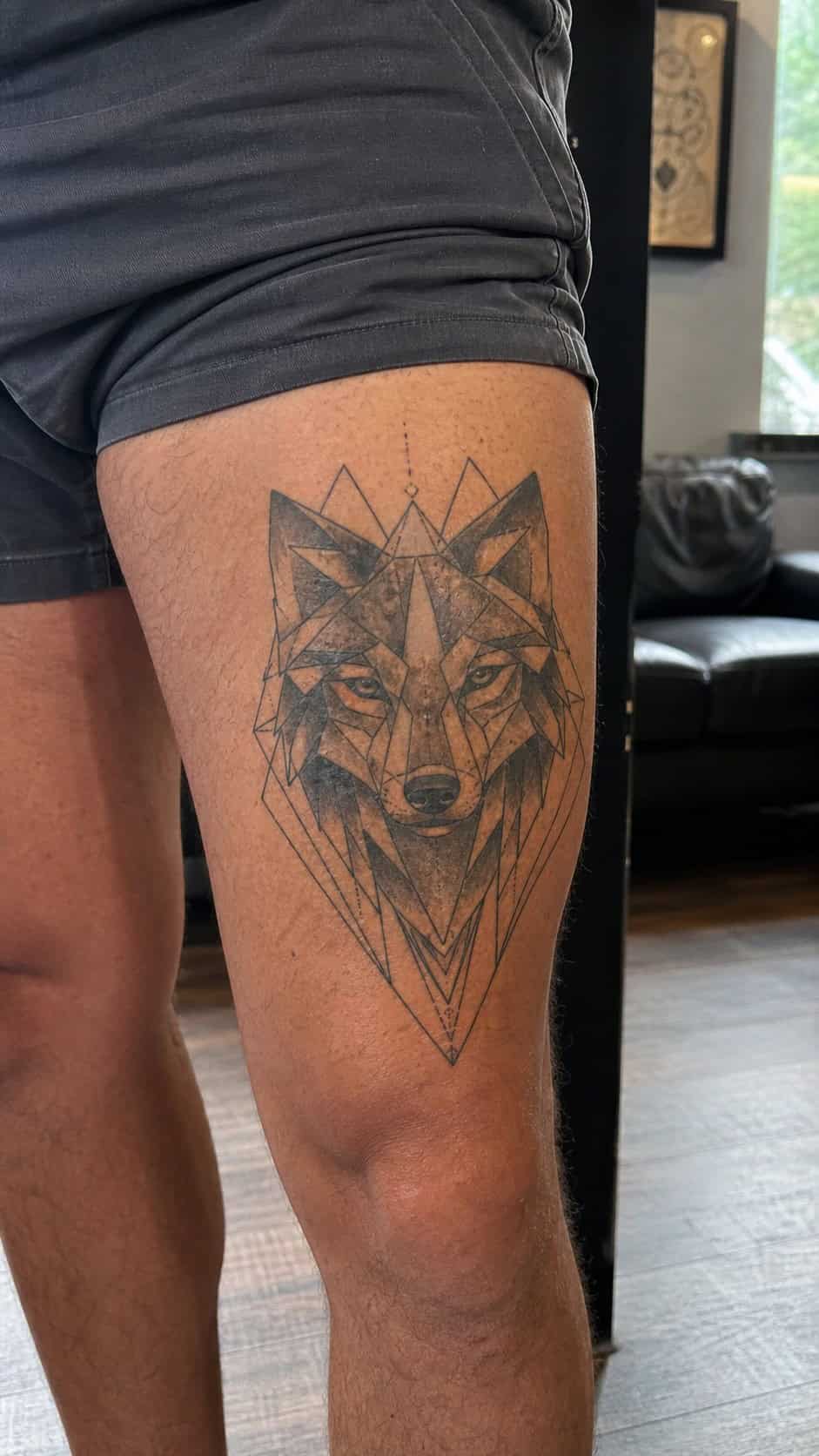 Feeling Bold? Try These 25 Killer Thigh Tattoo Ideas for Men 6 Healed geometric wolf head tattoo on a adult man's outer thigh, photographed in a natural relaxed documentary crop — study 1