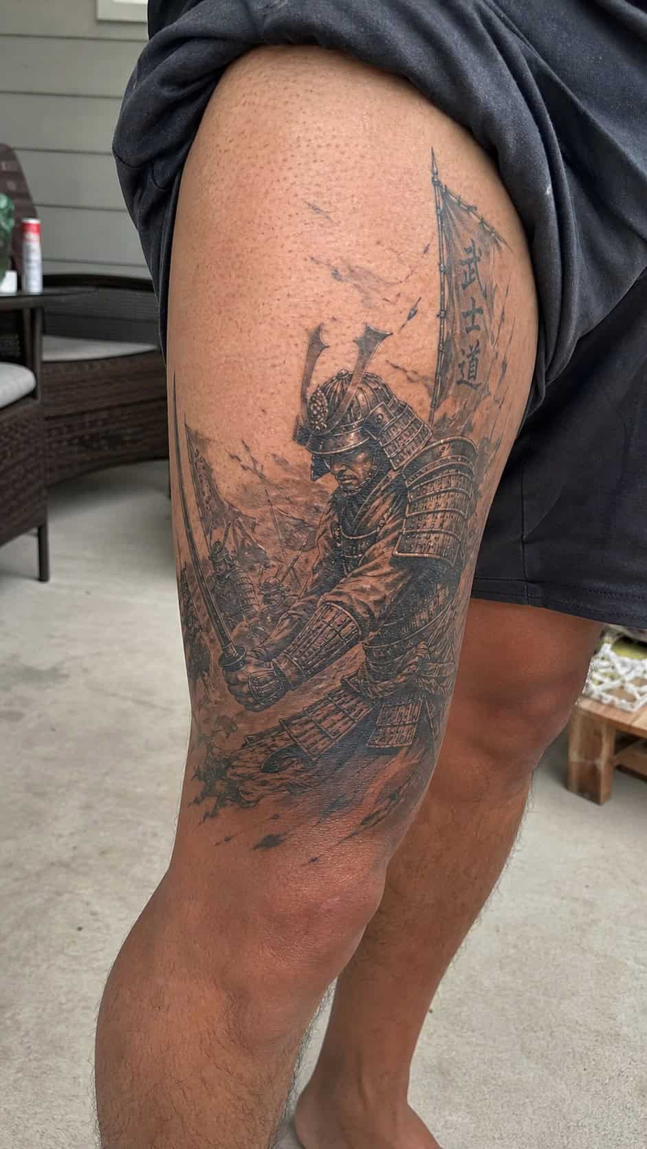 Feeling Bold? Try These 25 Killer Thigh Tattoo Ideas for Men 11 Healed samurai warrior in battle tattoo on a adult man's outer thigh, photographed in a natural casual close three-quarter view — study 1