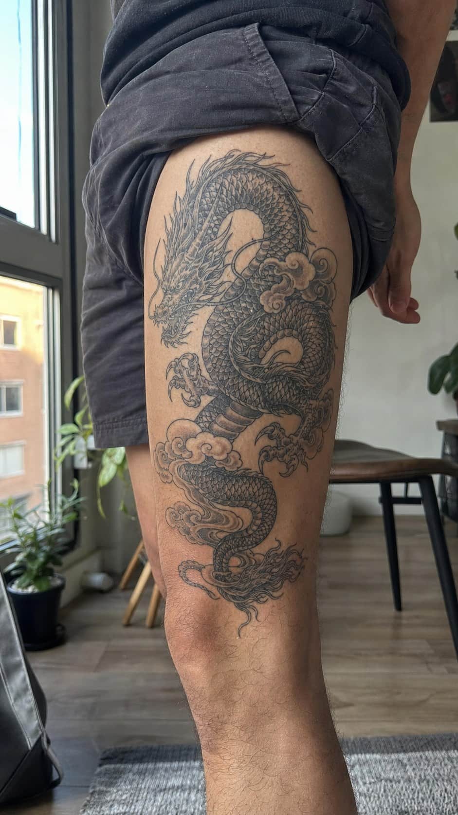 Feeling Bold? Try These 25 Killer Thigh Tattoo Ideas for Men 22 Healed detailed dragon coiling tattoo on a adult man's outer thigh, photographed in a natural slightly elevated close view — study 2