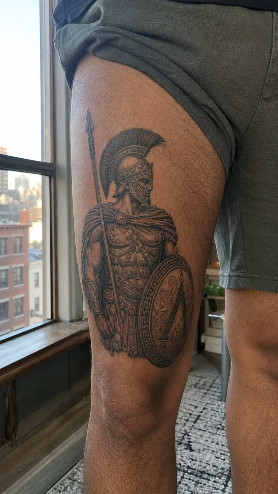 Feeling Bold? Try These 25 Killer Thigh Tattoo Ideas for Men 26 Healed ancient greek warrior tattoo on a adult man's outer thigh, photographed in a natural waist-height candid close-up — study 2