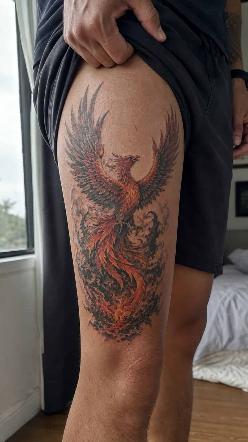 Feeling Bold? Try These 25 Killer Thigh Tattoo Ideas for Men 29 Healed mythical phoenix rising tattoo on a adult man's outer thigh, photographed in a natural slightly elevated close view — study 1