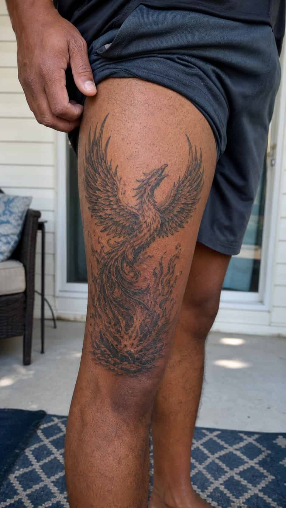 Feeling Bold? Try These 25 Killer Thigh Tattoo Ideas for Men 30 Healed mythical phoenix rising tattoo on a adult man's outer thigh, photographed in a natural waist-height candid close-up — study 2