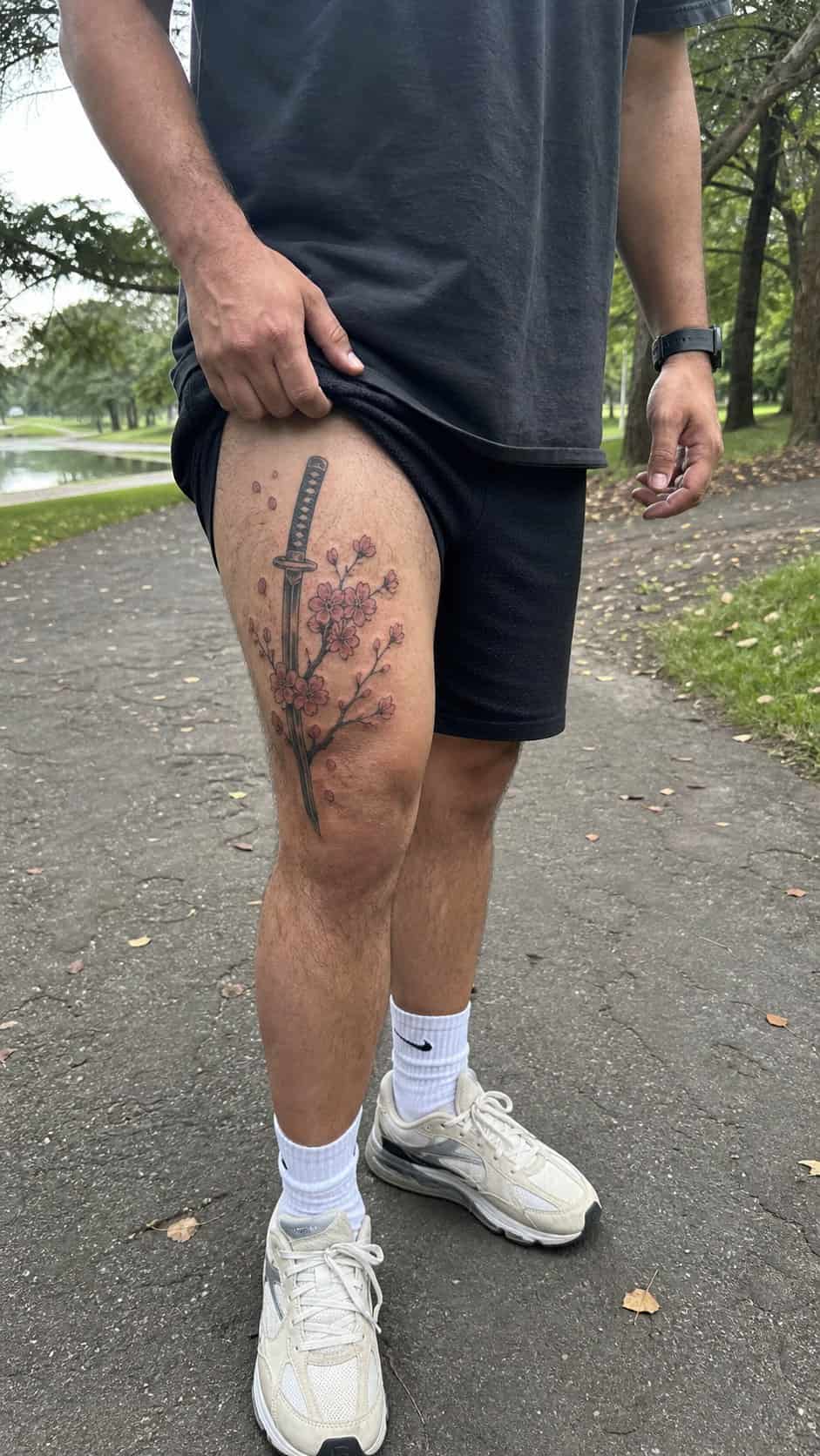 Feeling Bold? Try These 25 Killer Thigh Tattoo Ideas for Men 42 Healed samurai sword and cherry blossoms tattoo on a adult man's outer thigh, photographed in a natural relaxed documentary crop — study 2