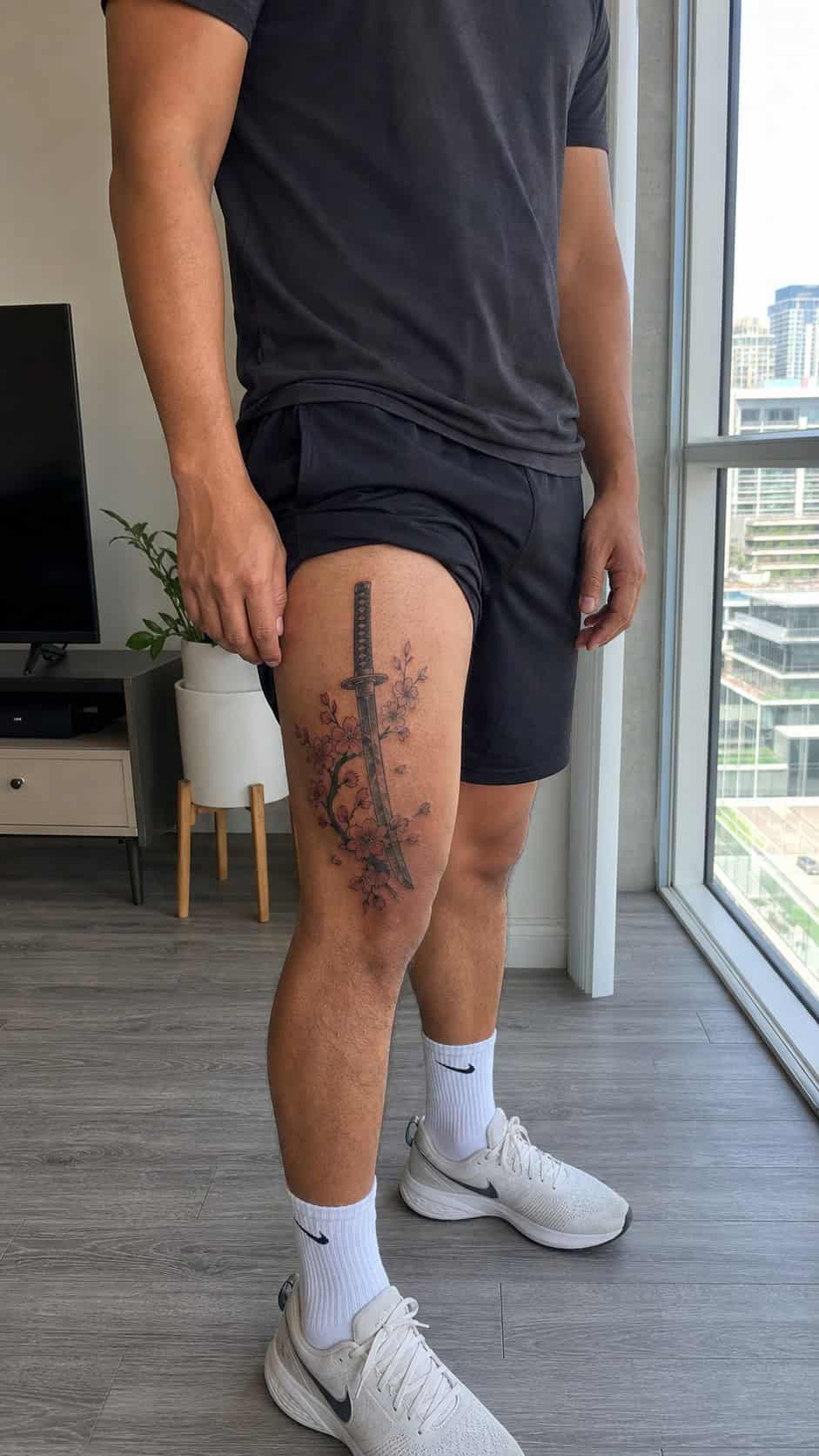 Feeling Bold? Try These 25 Killer Thigh Tattoo Ideas for Men 43 Healed samurai sword and cherry blossoms tattoo on a adult man's outer thigh, photographed in a natural casual close three-quarter view — study 3