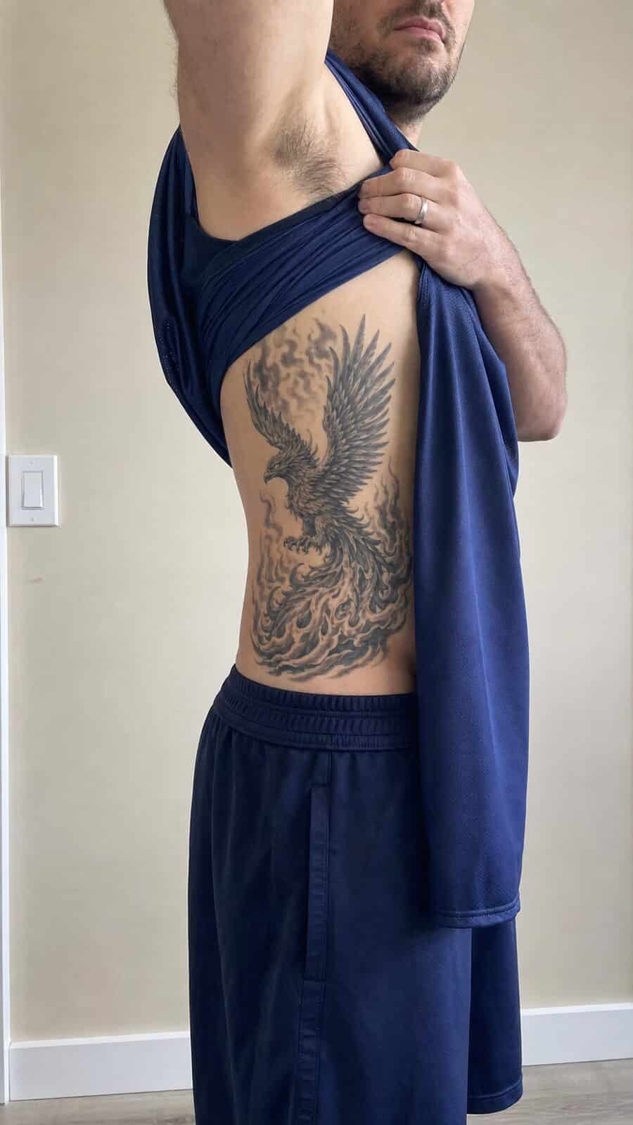 25 Rib Tattoos for Men Worth Considering 13 Healed phoenix rising tattoo on a adult man's side ribs, photographed in a natural relaxed documentary crop — study 1