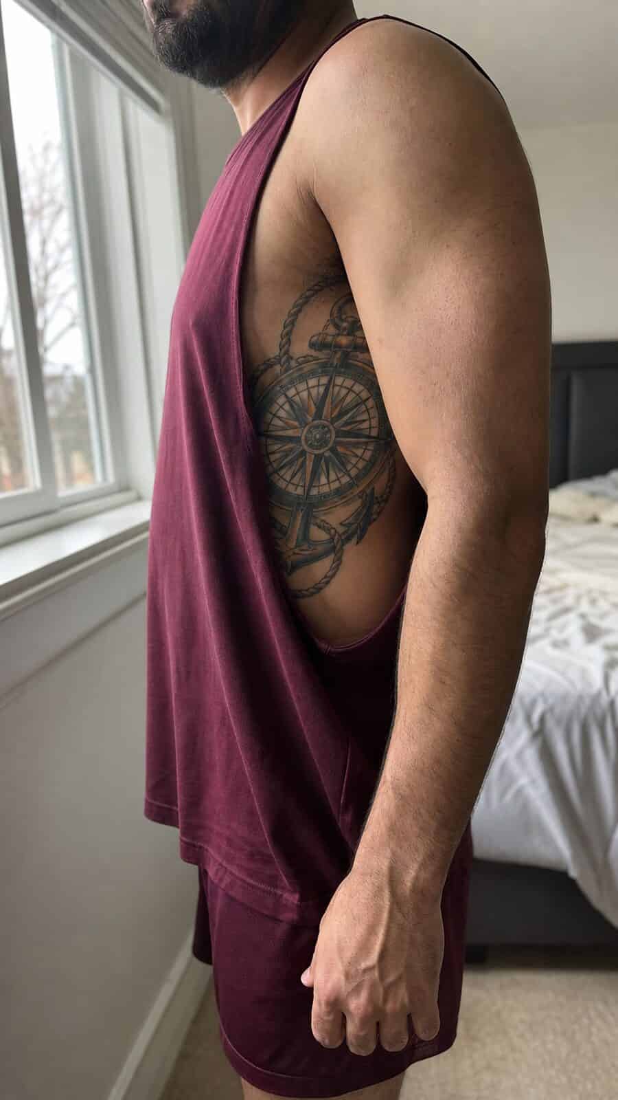 25 Rib Tattoos for Men Worth Considering 20 Healed nautical compass tattoo on a adult man's side ribs, photographed in a natural waist-height candid close-up — study 2