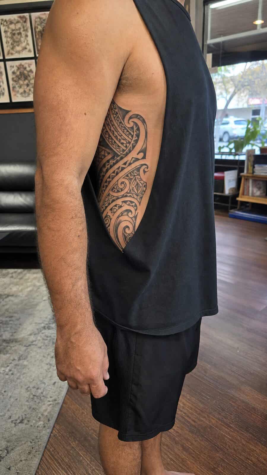 25 Rib Tattoos for Men Worth Considering 21 Healed tribal patterns tattoo on a adult man's side ribs, photographed in a natural casual close three-quarter view — study 1