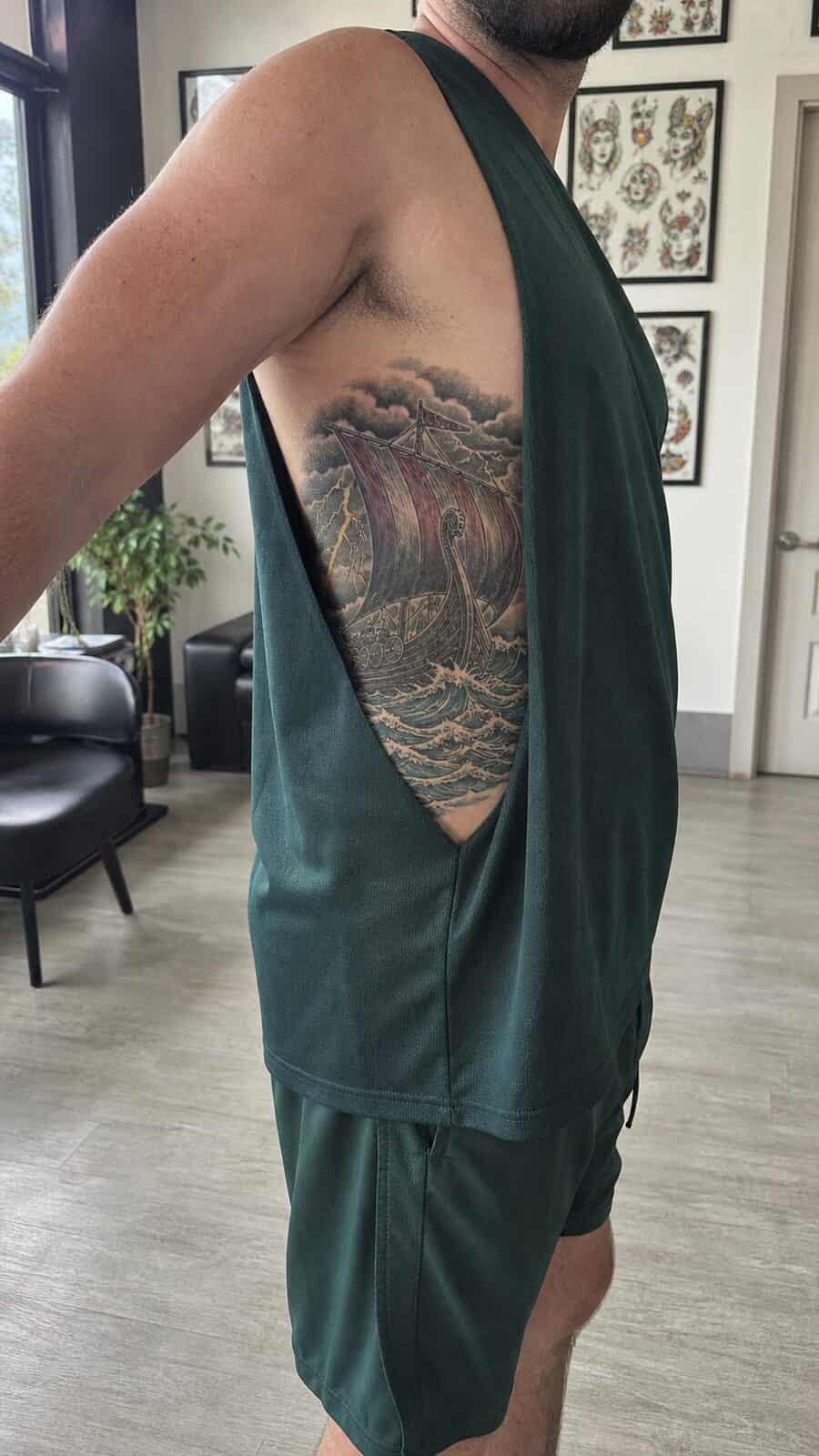 25 Rib Tattoos for Men Worth Considering 24 Healed viking ship tattoo on a adult man's side ribs, photographed in a natural slightly elevated close view — study 2