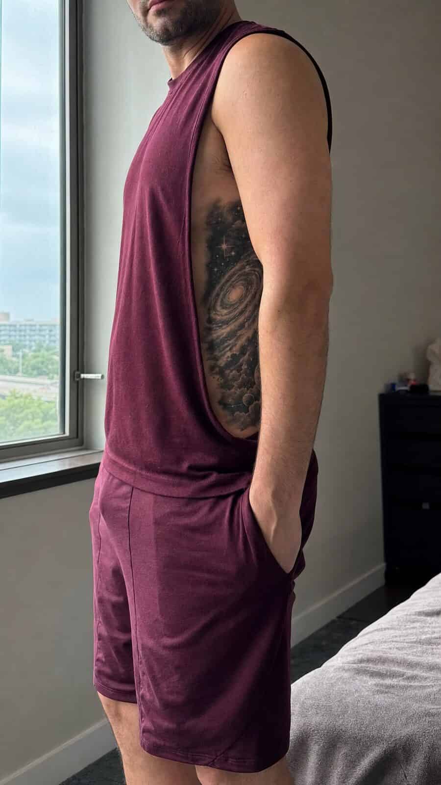 25 Rib Tattoos for Men Worth Considering 25 Healed cosmic galaxy tattoo on a adult man's side ribs, photographed in a natural casual close three-quarter view — study 1