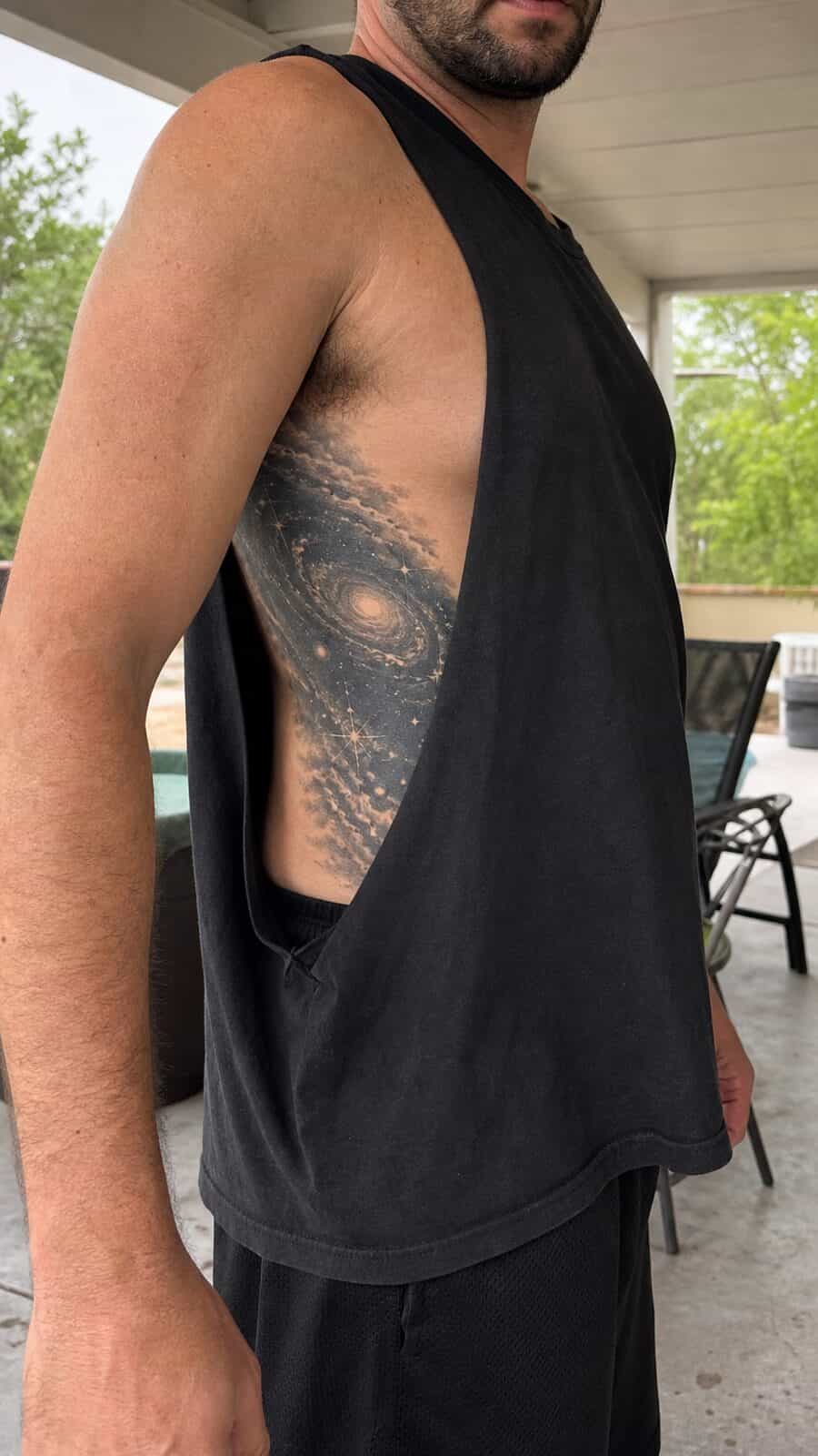 25 Rib Tattoos for Men Worth Considering 26 Healed cosmic galaxy tattoo on a adult man's side ribs, photographed in a natural straight-on close view, a touch off-center like a — study 2
