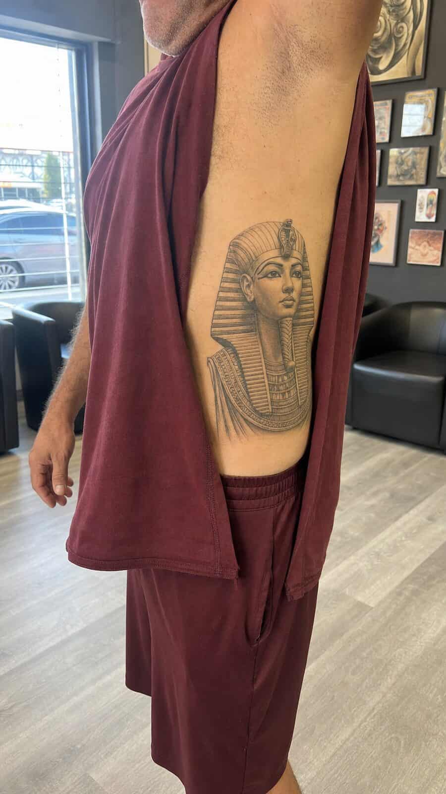 25 Rib Tattoos for Men Worth Considering 35 Healed egyptian pharaoh tattoo on a adult man's side ribs, photographed in a natural slightly elevated close view — study 2