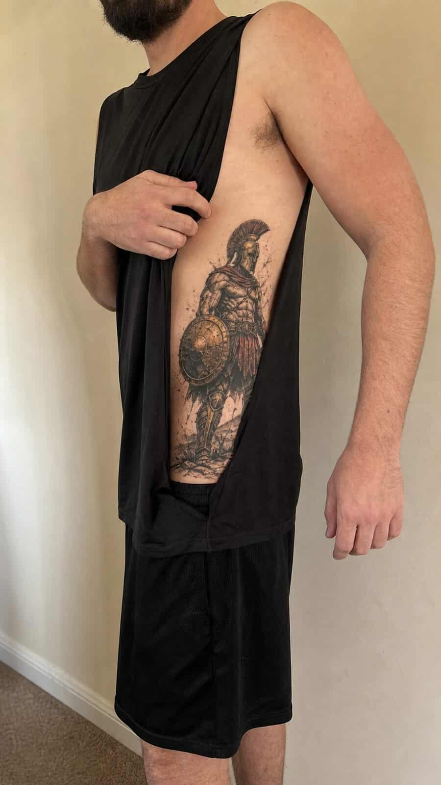 25 Rib Tattoos for Men Worth Considering 41 Healed warrior spartan tattoo on a adult man's side ribs, photographed in a natural straight-on close view, a touch off-center like a — study 2