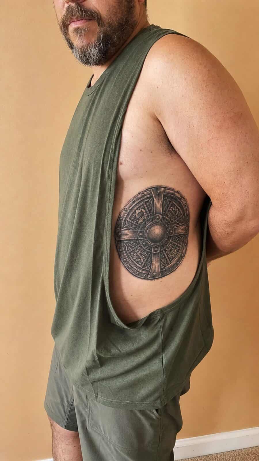25 Rib Tattoos for Men Worth Considering 47 Healed warrior’s shield tattoo on a adult man's side ribs, photographed in a natural straight-on close view, a touch off-center like a — study 1