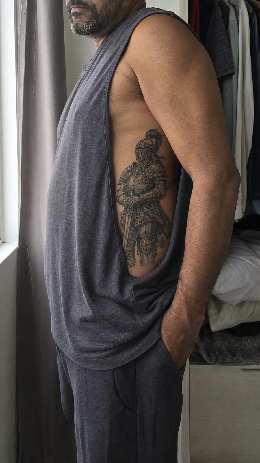 25 Rib Tattoos for Men Worth Considering 52 Healed knight in armor tattoo on a adult man's side ribs, photographed in a natural waist-height candid close-up — study 2