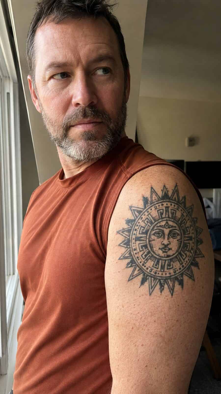 Unlock Your Next Ink: 25 Epic Upper Arm Tattoo Ideas for Men 53 Healed aztec sun tattoo on a adult man's outer upper arm, photographed in a natural relaxed documentary crop — study 2