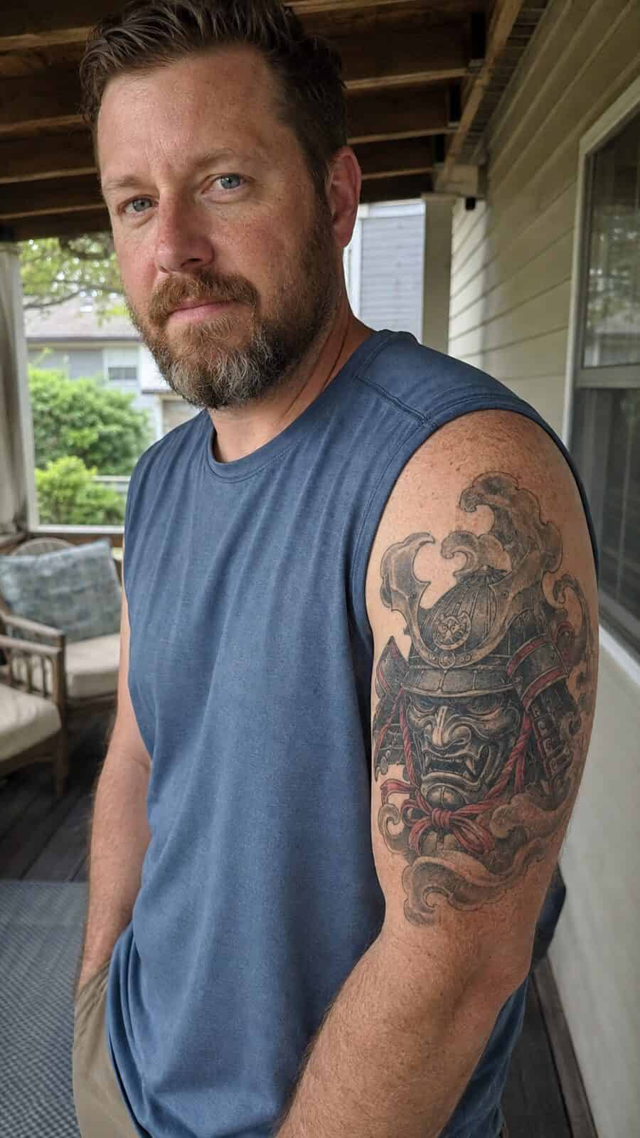 Unlock Your Next Ink: 25 Epic Upper Arm Tattoo Ideas for Men 61 Healed samurai mask tattoo on a adult man's outer upper arm, photographed in a natural waist-height candid close-up — study 1