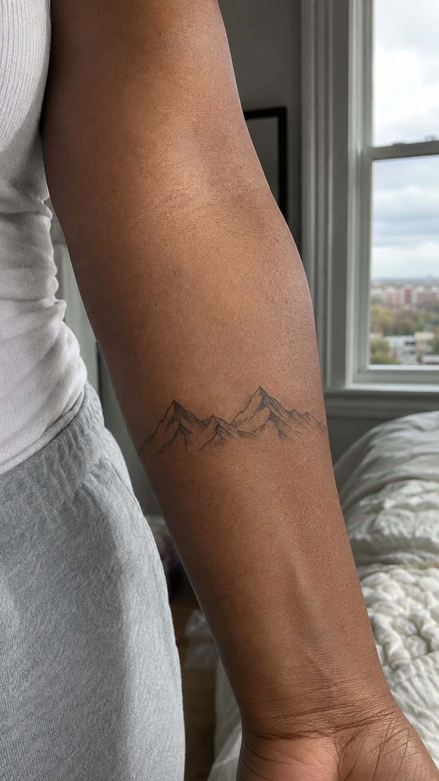 35 Forearm Tattoos for Women Worth Considering 11 Healed minimalist mountains tattoo on a adult woman's inner forearm, photographed in a natural gentle side angle that clearly shows — study 1