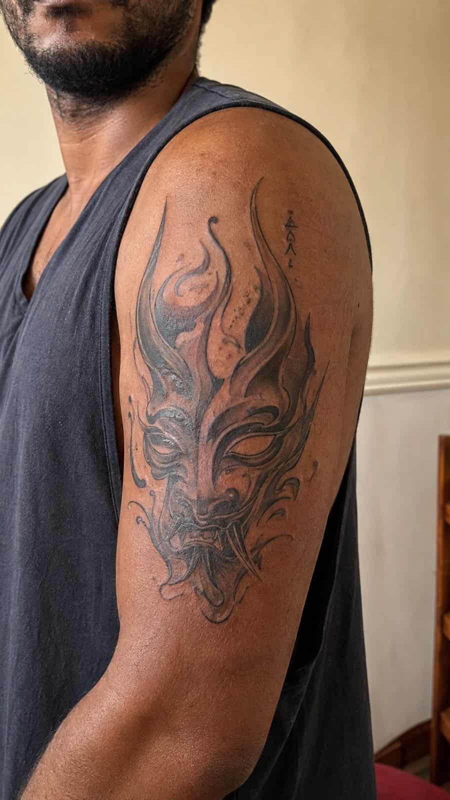 Unleash Your Dark Side: 23 Devilishly Unique Tattoo Ideas for Men 7 Healed abstract demon mask tattoo on a adult man's outer upper arm, photographed in a natural relaxed documentary crop — study 1