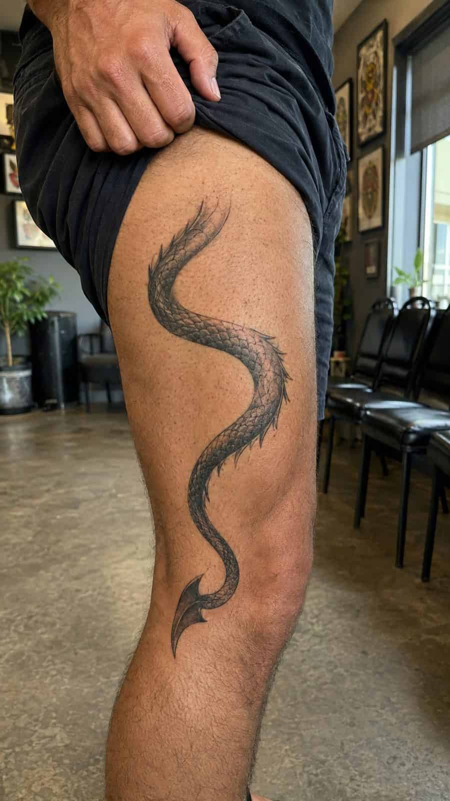 Unleash Your Dark Side: 23 Devilishly Unique Tattoo Ideas for Men 9 Healed serpentine devil tail tattoo on a adult man's outer thigh, photographed in a natural casual close three-quarter view — study 1
