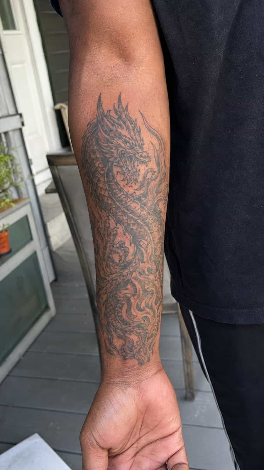 Unleash Your Dark Side: 23 Devilishly Unique Tattoo Ideas for Men 14 Healed infernal dragon tattoo on a adult man's inner forearm, photographed in a natural relaxed documentary crop — study 1