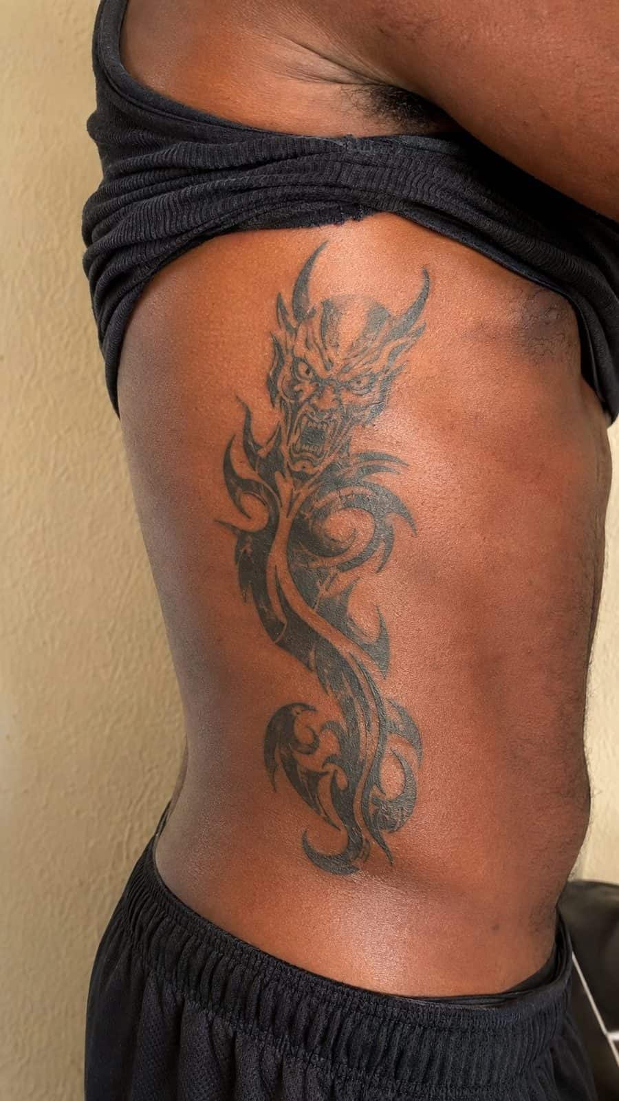 Unleash Your Dark Side: 23 Devilishly Unique Tattoo Ideas for Men 16 Healed tribal devil design tattoo on a adult man's side ribs, photographed in a natural waist-height candid close-up — study 1