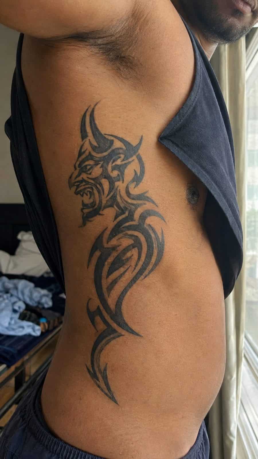 Unleash Your Dark Side: 23 Devilishly Unique Tattoo Ideas for Men 17 Healed tribal devil design tattoo on a adult man's side ribs, photographed in a natural relaxed documentary crop — study 2