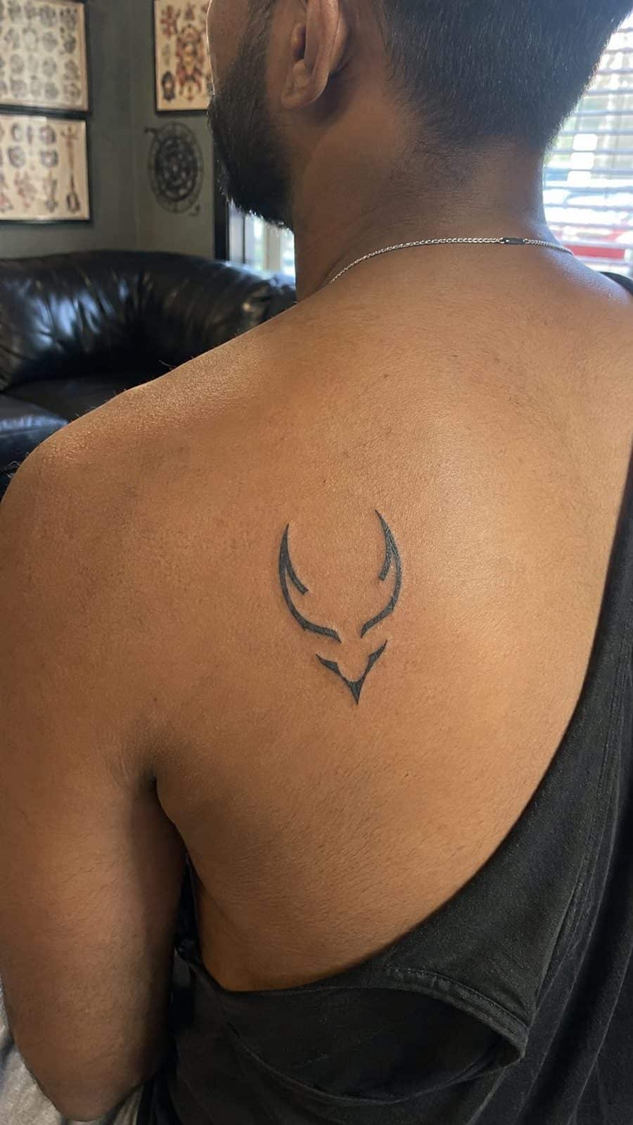Unleash Your Dark Side: 23 Devilishly Unique Tattoo Ideas for Men 28 Healed minimalist devil symbol tattoo on a adult man's upper back, photographed in a natural casual close three-quarter view — study 1