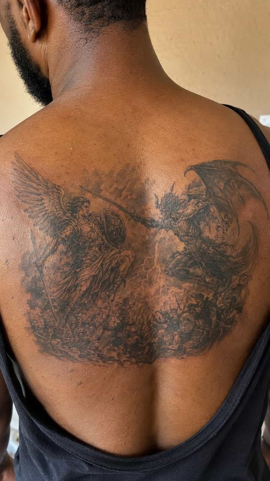 Unleash Your Dark Side: 23 Devilishly Unique Tattoo Ideas for Men 44 Healed epic battle: good vs evil tattoo on a adult man's upper back, photographed in a natural straight-on close view, a touch — study 2