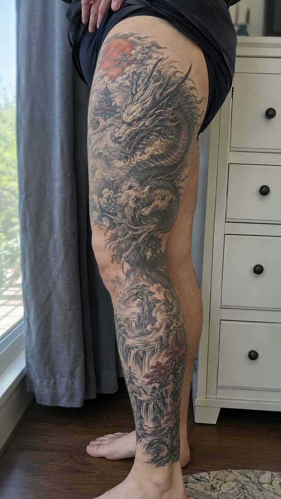 32 Gorgeous Female Leg Sleeve Tattoos 18 Healed mythical dragon realm tattoo on a adult woman's full outer leg sleeve, photographed in a natural waist-height candid close-up — study 1