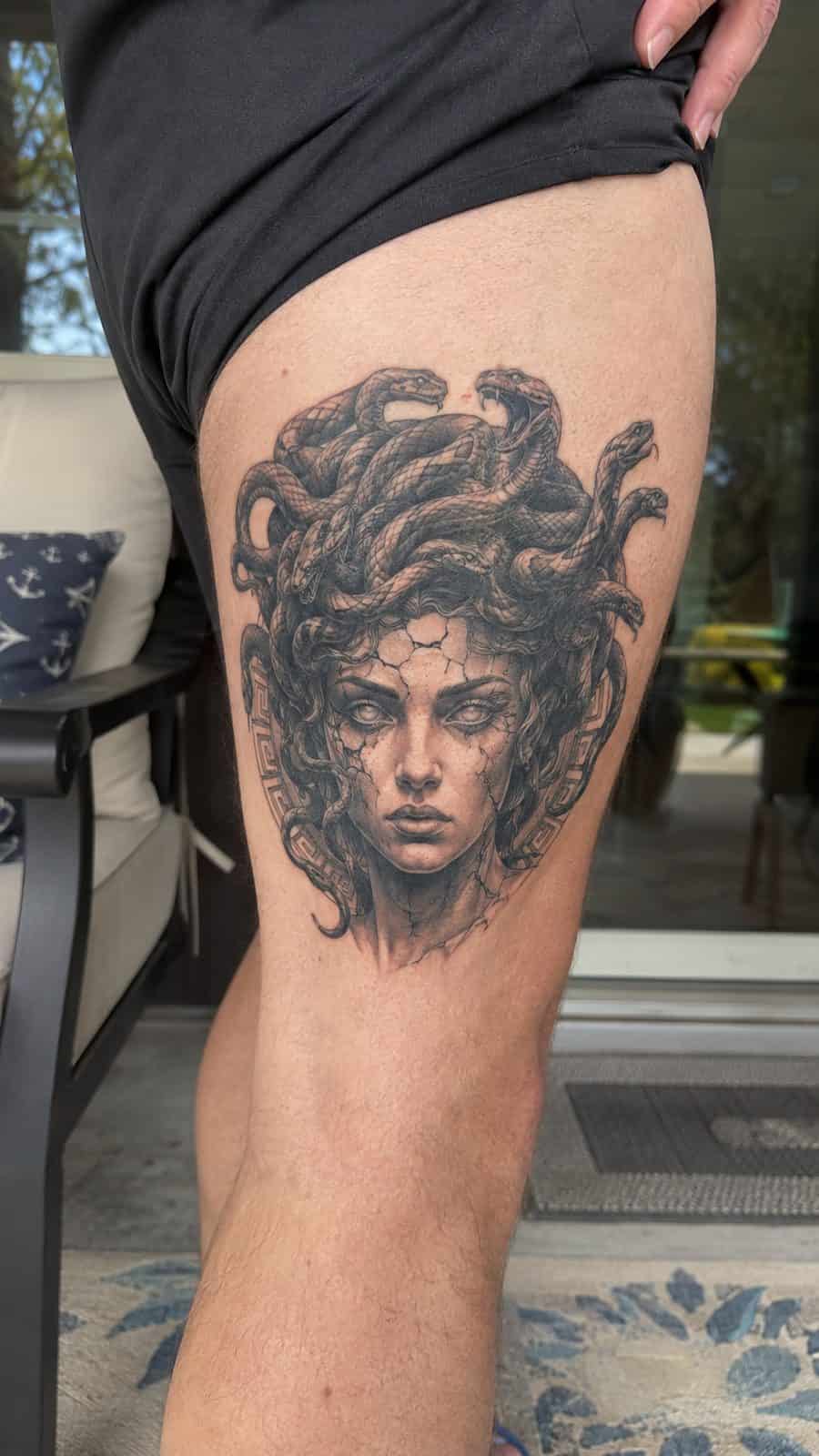 Modern Spartan: 18 Greek Tattoo Ideas Every Man Should Consider 10 Healed medusa's gaze tattoo on a adult man's outer thigh, photographed in a natural relaxed documentary crop — study 1