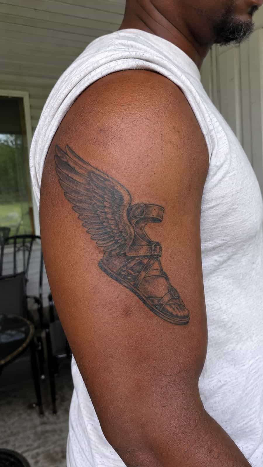 Modern Spartan: 18 Greek Tattoo Ideas Every Man Should Consider 19 Healed hermes's winged sandals tattoo on a adult man's outer upper arm, photographed in a natural slightly elevated close view — study 2
