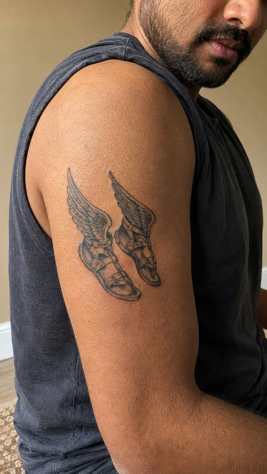 Modern Spartan: 18 Greek Tattoo Ideas Every Man Should Consider 20 Healed hermes's winged sandals tattoo on a adult man's outer upper arm, photographed in a natural waist-height candid close-up — study 3