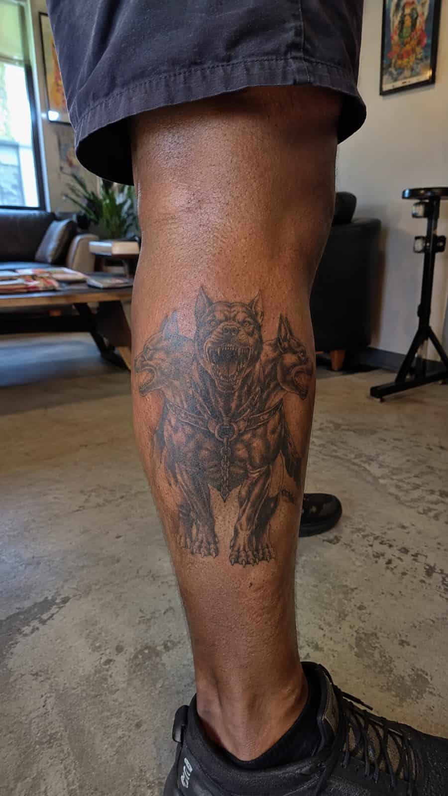 Modern Spartan: 18 Greek Tattoo Ideas Every Man Should Consider 36 Healed cerberus tattoo on a adult man's outer calf, photographed in a natural gentle side angle that clearly shows how the ink wraps — study 1