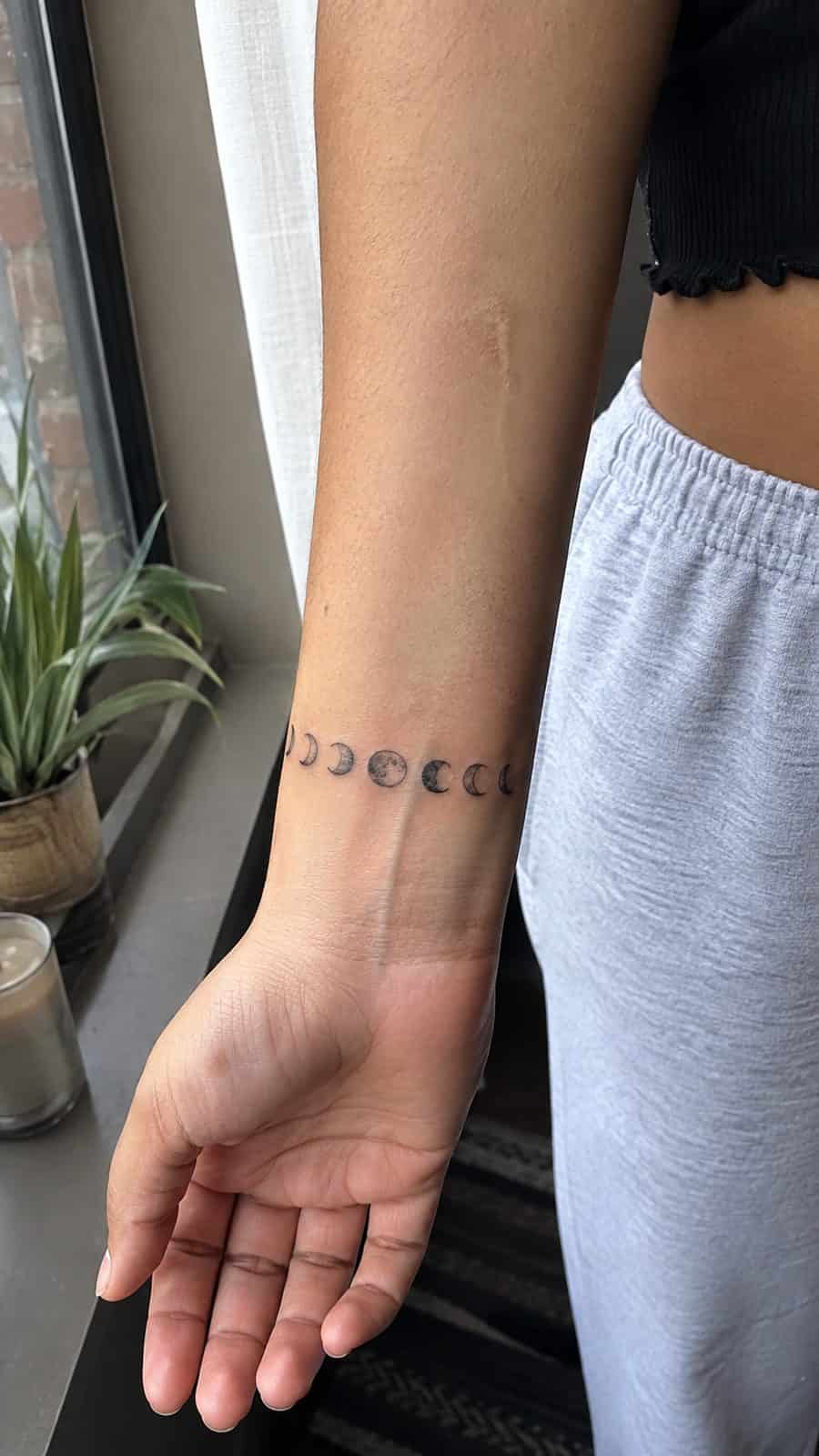 Wrist Tattoos Women Are Raving About: Discover the 28 Most Gorgeous Designs 4 Healed minimalist moon phases tattoo on a adult woman's inner wrist, photographed in a natural waist-height candid close-up — study 1