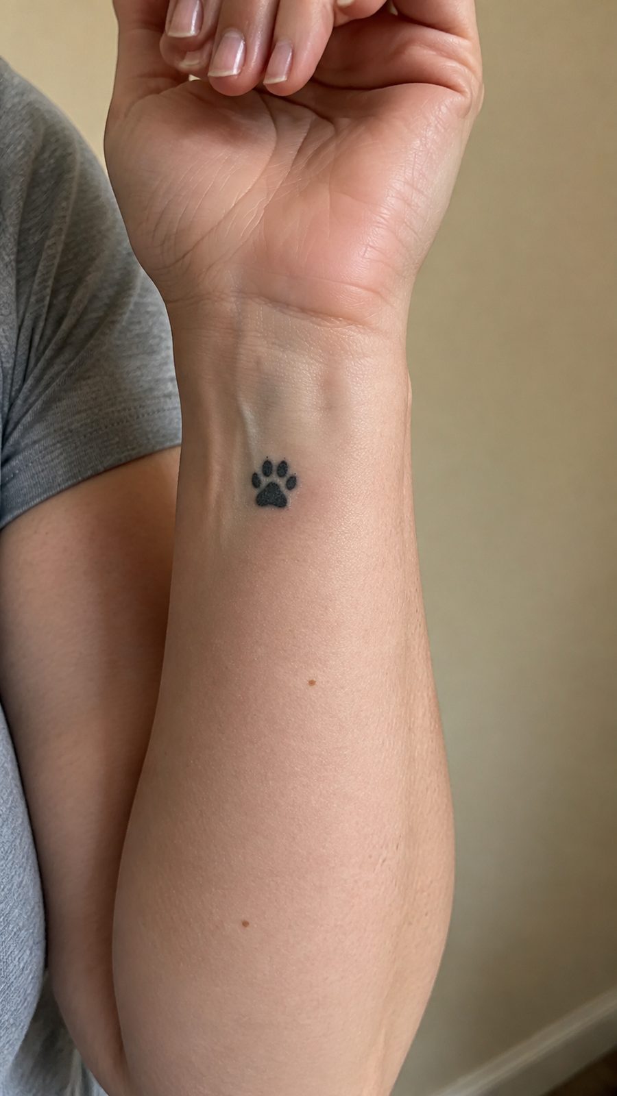 Wrist Tattoos Women Are Raving About: Discover the 28 Most Gorgeous Designs 25 Healed paw print tribute tattoo on a adult woman's inner wrist, photographed in a natural slightly elevated close view — study 2