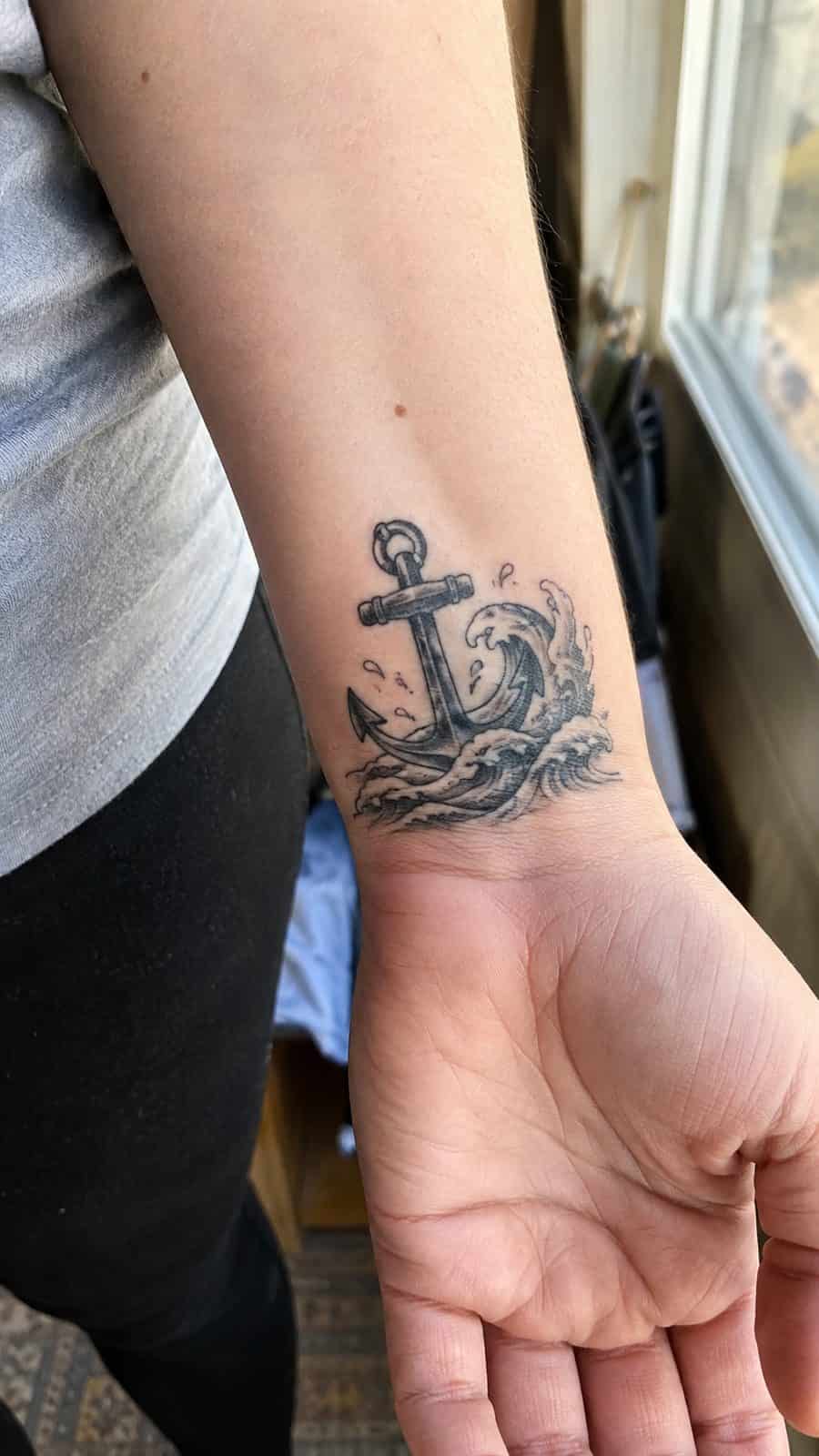 Wrist Tattoos Women Are Raving About: Discover the 28 Most Gorgeous Designs 32 Healed anchor with waves tattoo on a adult woman's inner wrist, photographed in a natural waist-height candid close-up — study 1