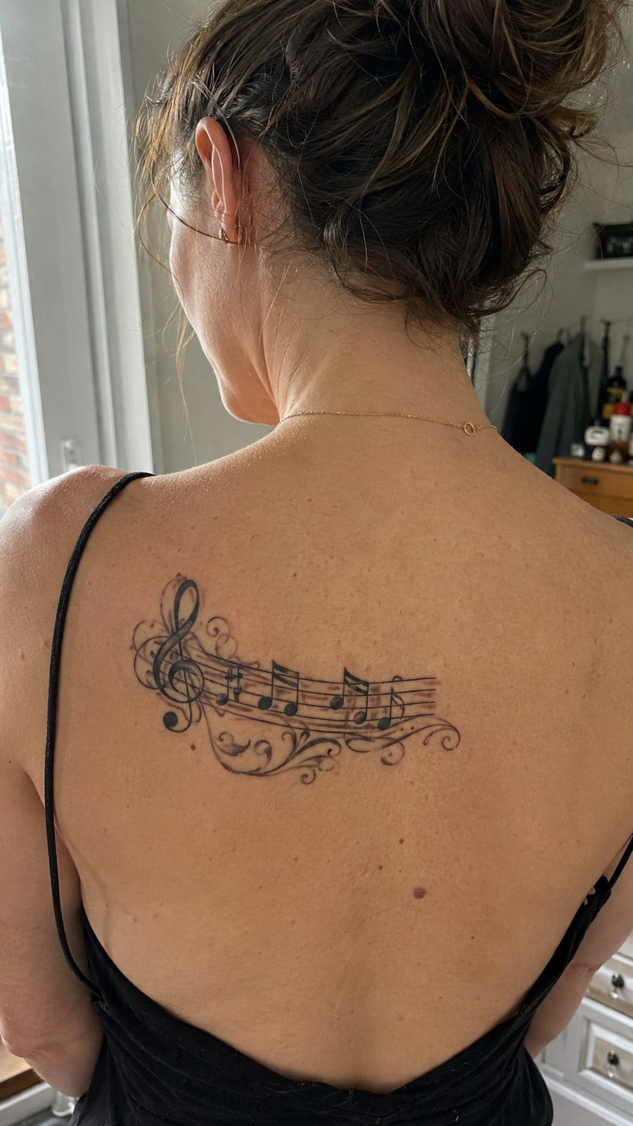 20 Edgy Grunge Tattoo Ideas for Women Who Break the Rules 9 Healed vintage music notes tattoo on a adult woman's upper back, photographed in a natural waist-height candid close-up — study 1