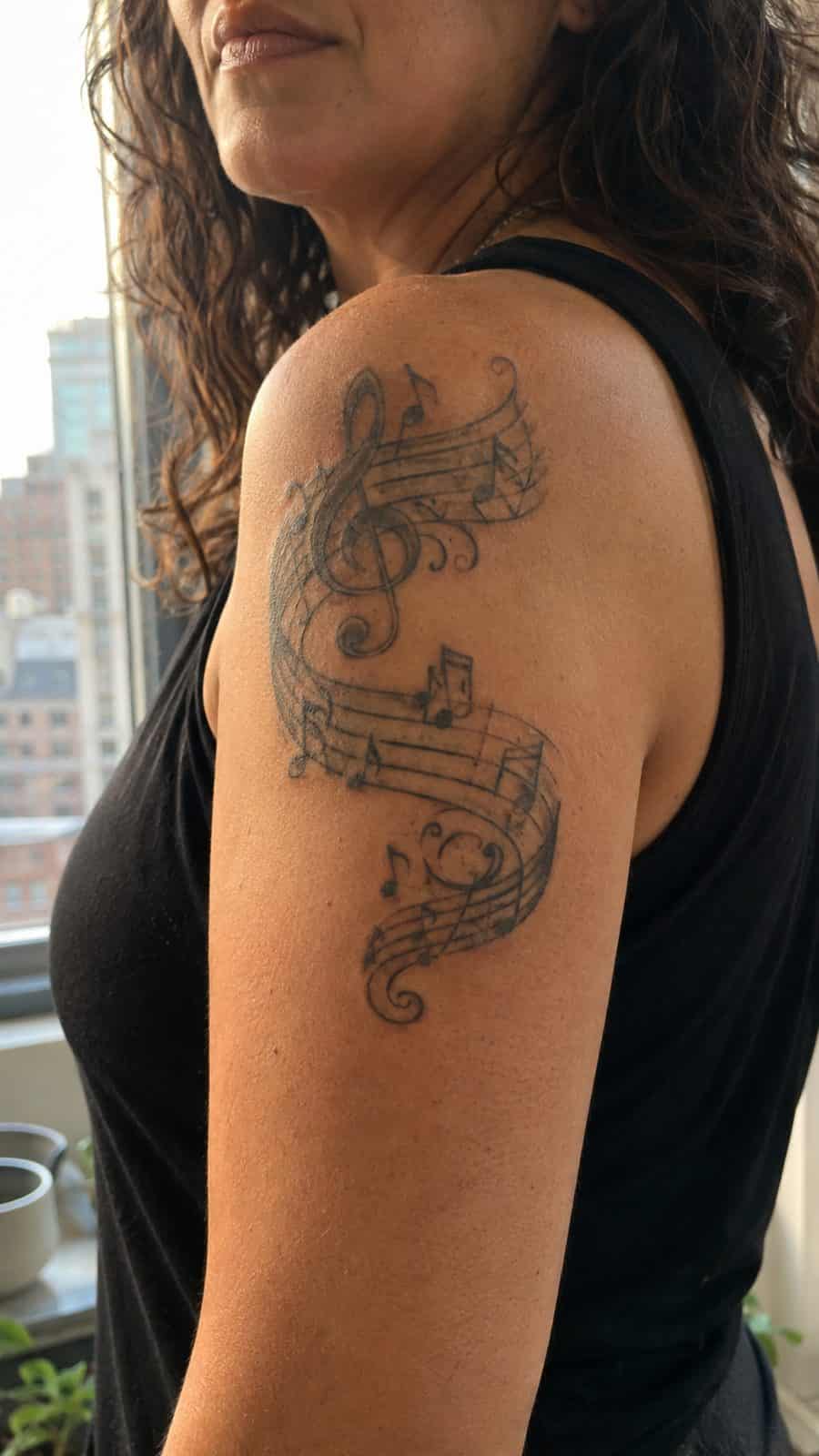 20 Edgy Grunge Tattoo Ideas for Women Who Break the Rules 10 Healed vintage music notes tattoo on a adult woman's shoulder, photographed in a natural relaxed documentary crop — study 2