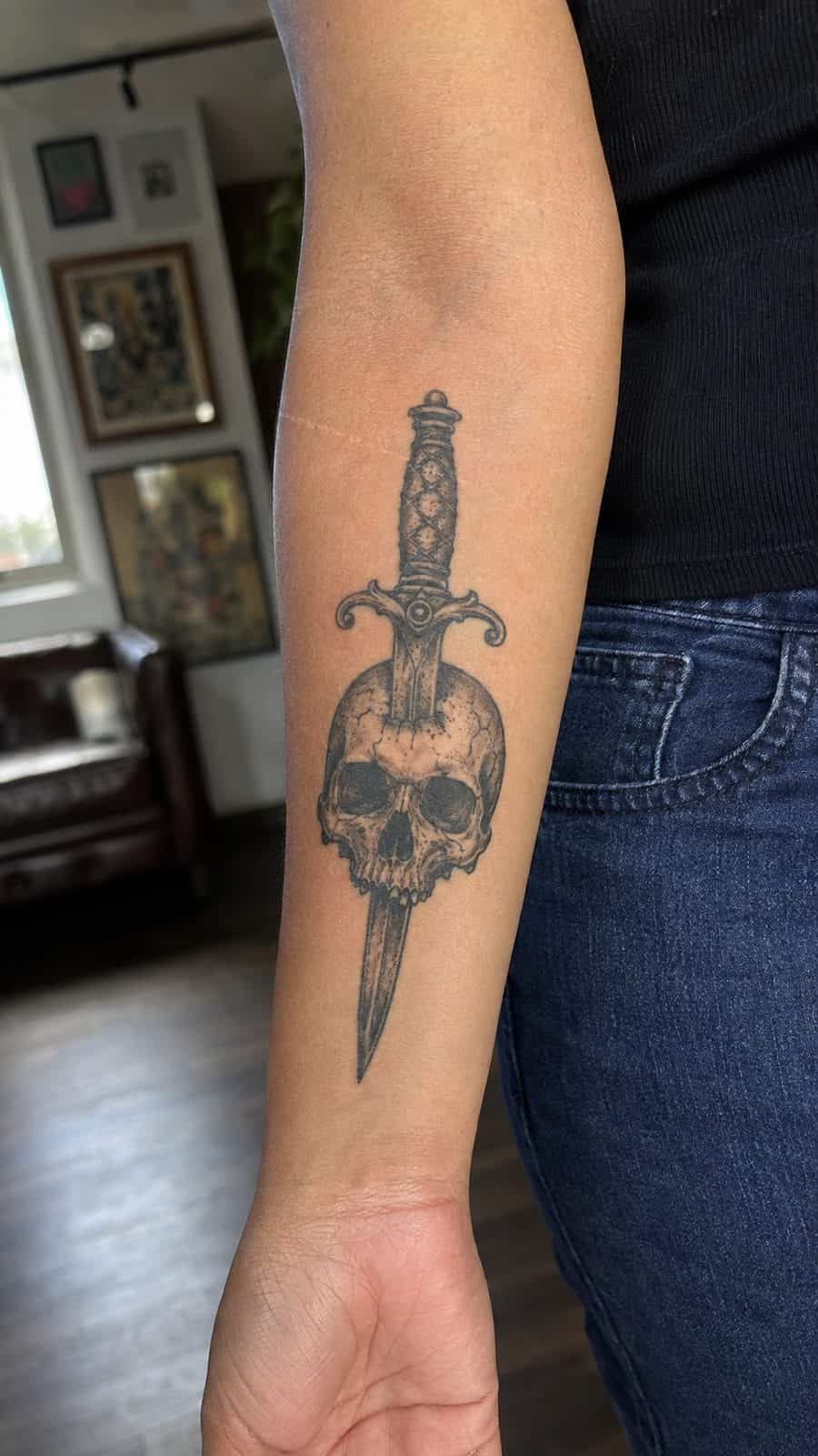 20 Edgy Grunge Tattoo Ideas for Women Who Break the Rules 13 Healed grunge skull and dagger tattoo on a adult woman's inner forearm, photographed in a natural casual close three-quarter view — study 3