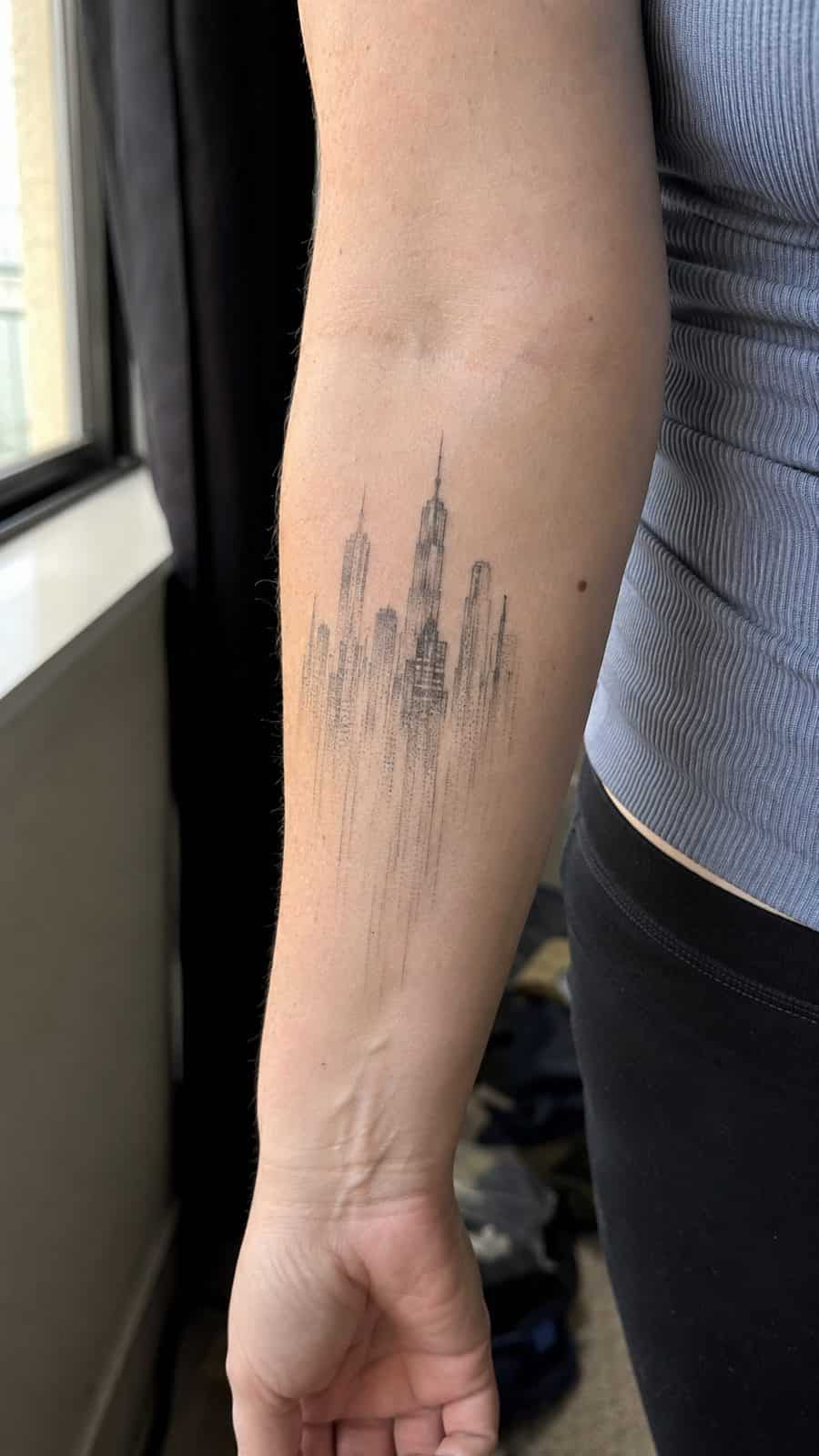 20 Edgy Grunge Tattoo Ideas for Women Who Break the Rules 21 Healed faded cityscape tattoo on a adult woman's inner forearm, photographed in a natural relaxed documentary crop — study 1