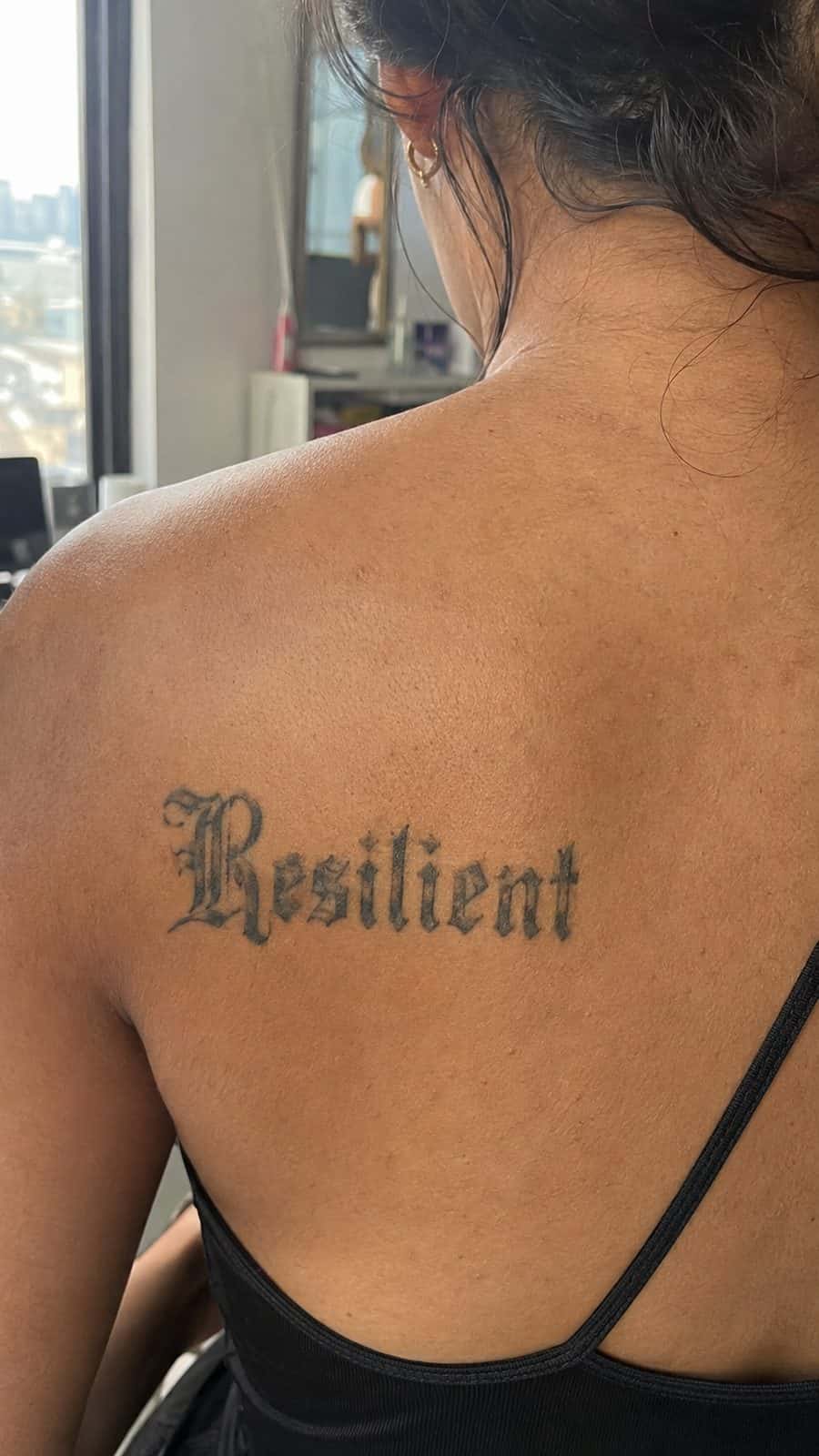 20 Edgy Grunge Tattoo Ideas for Women Who Break the Rules 49 Healed gothic letters tattoo on a adult woman's upper back, photographed in a natural slightly elevated close view — study 3